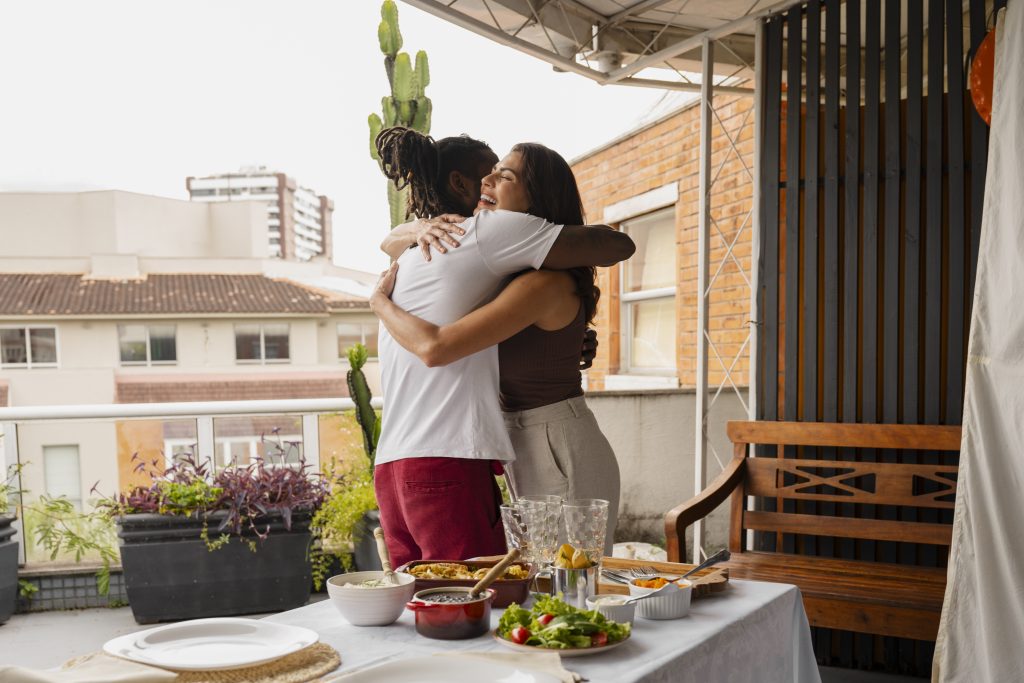 Duas pessoas se abraçando felizes no aconchegante espaço de uma varanda gourmet.